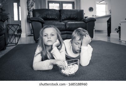 Coronavirus Lockdow. Bored Little Girl And Sad Boy Watching Tv In Isolation At Home During Quarantine COVID 19 Outbreak. Mandatory Lockdowns And School Closures Impact On Children Mental Health.