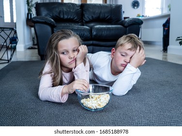 Coronavirus Lockdow. Bored Little Girl And Sad Boy Watching Tv In Isolation At Home During Quarantine COVID 19 Outbreak. Mandatory Lockdowns And School Closures Impact On Children Mental Health.