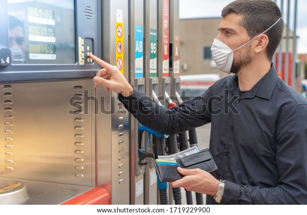 Coronavirus. Man with\
face mask at gas pump station paying for gasoline. Automotive\
industry or transportation and ownership concept. Delivery service\
concept. Isolated
