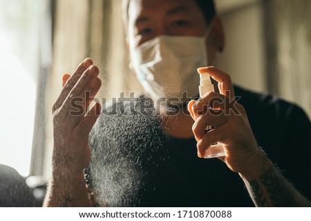 Coronavirus. Man wearing in medical protective mask cleaning hands with sanitizer spray in house to prevent Coronavirus, Covid-19, flu. Spray bottle. Virus and illness protection. Stock foto © 