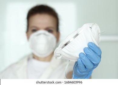 Coronavirus, N95 respirator, FFP2, COVID-19 concept. Medic, nurse with face mask and blue nitride  gloves  sharing protective respirator. Selective focus. 