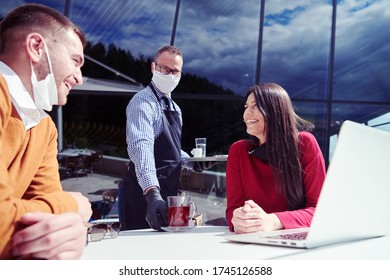 Coronavirus Outbreak Group Of Casual Business People In Outdoor Restaurant Wearing Protective Medical Mask, Business Team Collaborating And Brainstorming Business Ideas  While Working On Laptop