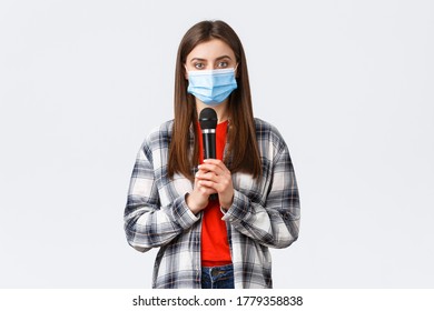 Coronavirus Outbreak, Leisure On Quarantine, Social Distancing And Emotions Concept. Woman In Medical Mask Performing Song Or Stand-up, Holding Microphone Want Be Heard, White Background