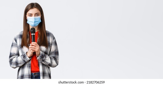 Coronavirus Outbreak, Leisure On Quarantine, Social Distancing And Emotions Concept. Girl In Medical Mask Performing Song Or Stand-up, Holding Microphone Want Be Heard, White Background