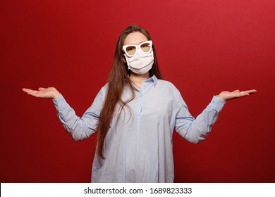 Coronavirus Pandemic, Close-up Portrait Of Young Woman On Red Background In Protective Medical Mask, Uncertainty