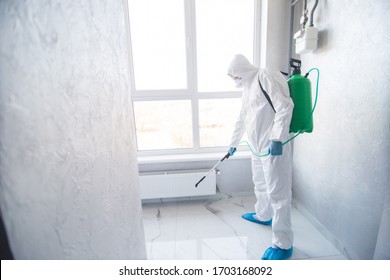 Coronavirus Pandemic. A disinfector in a protective suit and mask sprays disinfectants in house or office. Protection agsinst COVID-19 disease. Prevention of spreding pneumonia virus with surfaces. - Shutterstock ID 1703168092