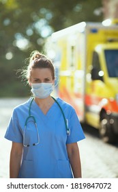 Coronavirus Pandemic. Modern Medical Doctor Woman In Uniform With Stethoscope And Medical Mask Outside Near Ambulance.