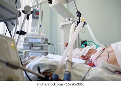 Coronavirus pandemic. Patient with coronavirus pneumonia in critical state. Intubated senior under ventilator lying in coma in intensive care department.