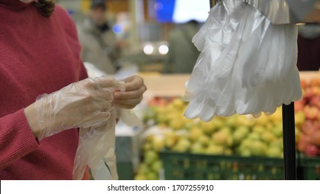 Coronavirus Pandemic. A Woman In A Supermarket Puts On Disposable Plastic Gloves To Protect Against Coronavirus, Close-up. Precautions Against The Spread Of The Disease.