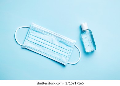 Coronavirus Prevention Hand Sanitizer Gel And Protection Face Mask On Blue Background. Top View.