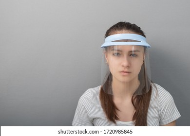 Coronavirus Prevention Young woman in a protective mask screen with a visor on a gray background