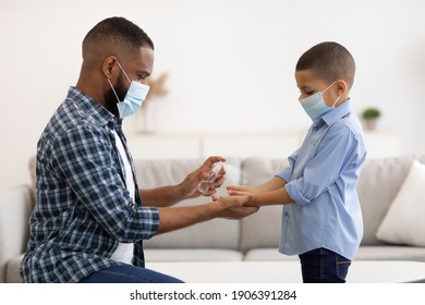 Coronavirus Protection. African Father Spraying Sanitizer On Son's Hands Cleaning Arms At Home, Wearing Protective Face Masks For Covid-19 Prevention. Health Care Concept - Powered by Shutterstock