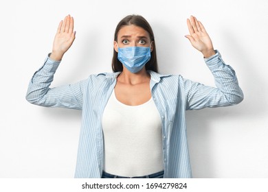 Coronavirus Quarantine Breaker. Woman In Mask Raising Hands Caught On Breaking Self-Quarantine Rules Standing Over White Background