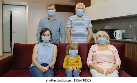 Coronavirus Quarantine Lockdown Concept. Mother, Father, Daughter, Senior Grandparents In Medical Masks On Faces At Home. Multigenerational Family Wearing Protective Masks. Life In Covid-19 Pandemic