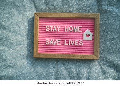 Coronavirus Quote Stay Home, Save Lives Pink Felt Board Sign With Message Of Self Isolation For Social Responsability On Home Sofa Background. COVID-19 Text To Promote Staying At Home.