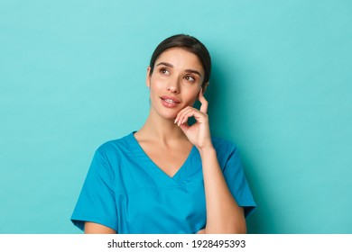 Coronavirus, Social Distancing And Health Concept. Close-up Of Thoughtful Female Healthcare Worker In Scrubs, Looking Left And Thinking, Standing Over Blue Background