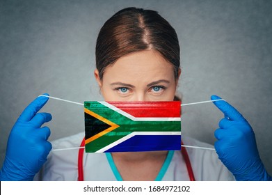 Coronavirus In South Africa Female Doctor Portrait Hold Protect Face Surgical Medical Mask With South Africa National Flag. Illness, Virus Covid-19 In South Africa, Concept Photo