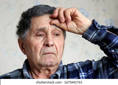 Coronavirus symptoms, elderly man put his hand on forehead. Sick male with gray hair, concept of headache, pressure or cold and flu - Shutterstock ID 1673441761