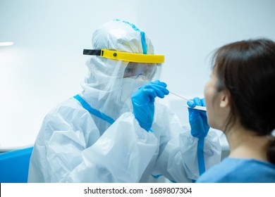 Coronavirus test - Medical worker taking a throat swab for coronavirus sample from a potentially infected woman with the isolation gown or protective suits and surgical face masks