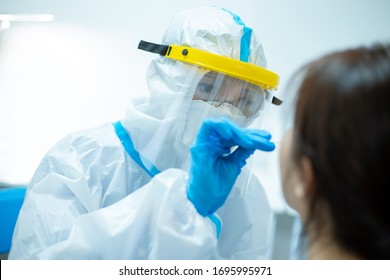 Coronavirus test - Medical worker taking a swab for corona virus sample from potentially infected woman with the isolation gown or protective suits and surgical face masks