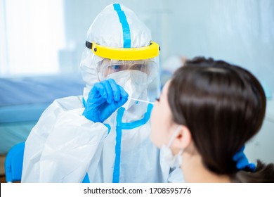 Coronavirus test - Medical worker taking a swab for corona virus sample from potentially infected woman with the isolation gown or protective suits and surgical face masks - Shutterstock ID 1708595776