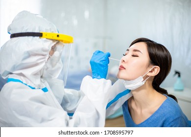 Coronavirus test - Medical worker taking a swab for corona virus sample from potentially infected woman with the isolation gown or protective suits and surgical face masks - Shutterstock ID 1708595797