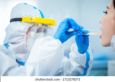 Coronavirus test - Medical worker taking a throat swab for coronavirus sample from a potentially infected woman with the isolation gown or protective suits and surgical face masks - Shutterstock ID 1713278371