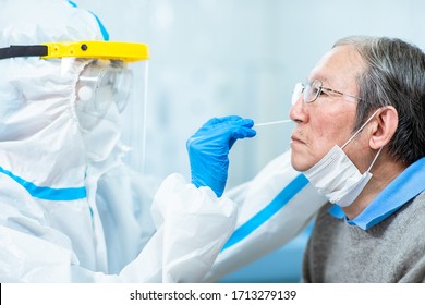 Coronavirus test - Medical worker taking a swab for corona virus sample from potentially infected elder man with the isolation gown or protective suits and surgical face masks