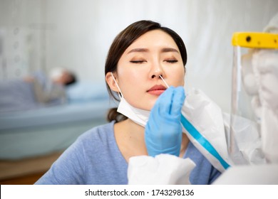 Coronavirus test - Medical worker taking a swab for corona virus sample from potentially infected woman with the isolation gown or protective suits and surgical face masks - Shutterstock ID 1743298136
