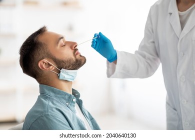 Coronavirus Testing Procedure. Doctor Making Nasal PCR Test For Millennial Guy, Using Swab Stick At Home. Young Caucasian Man Making Coronavirus Diagnostics. Health Care Concept