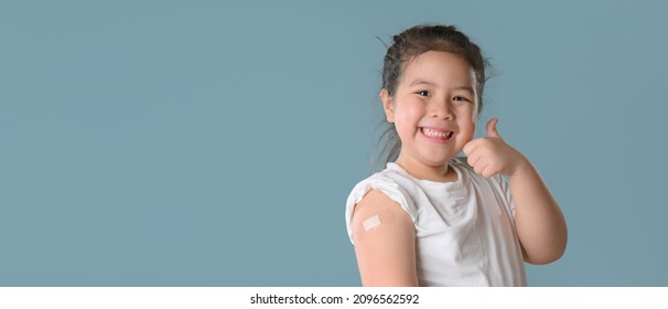 Coronavirus Vaccination Advertisement. Happy Vaccinated Little asian girl Showing Arm With Plaster Bandage After Covid-19 Vaccine Injection Posing Over Blue Background,  - Powered by Shutterstock