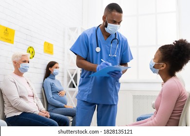 Coronavirus Vaccination Concept. African American Doctor Talking With Patient Teen Girl Before Covid-19 Vaccine Injection Sitting In Hospital. Corona Virus Protection And Medical Immunization