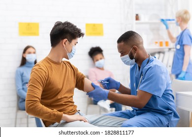 Coronavirus Vaccination. Doctor Vaccinating Asian Male Patient Giving Covid-19 Vaccine Injection In Arm Working In Hospital. Corona Virus Protection, Covid Population Immunization Campaign - Shutterstock ID 1828811177