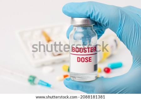 Coronavirus vaccination. Medical worker holds bottle with inscription Booster dose before injection
