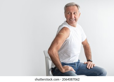 Coronavirus Vaccination. Senior Man Vaccinated With Antiviral Vaccine Showing Arm With Adhesive Bandage And Looking Aside At Copy Space Sitting In Studio Over Gray Background. Covid-19 Protection - Powered by Shutterstock