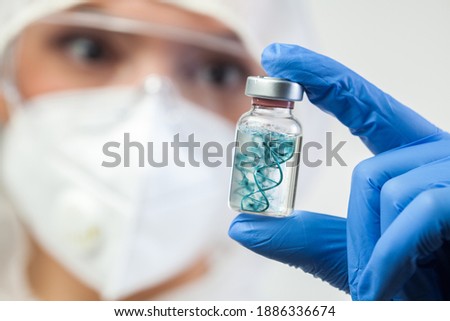 Coronavirus vaccine concept,UK doctor medical lab scientist holding glass phial ampoule containing COVID-19 vaccine,double helix DNA floating in liquid,immunization research for novel SARS virus cure