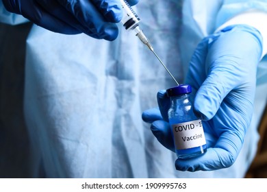 Coronavirus Vaccine And A Syringe In The Hands Of A Doctor Or Nurse. The Concept Of The Fight Against Covid