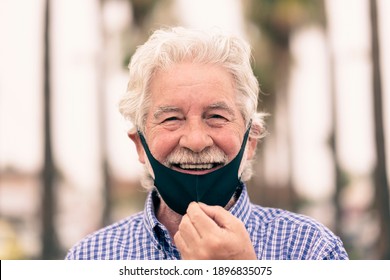 Coronavirus. White-haired Senior Man Takes Off The Protective Face Mask To Smile At Camera.