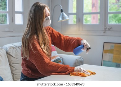 Coronavirus. Woman With Face Mask And Rubber Gloves Cleaning Stuff With A Disinfectant At Home During The Coronavirus Epidemic. Infection Prevention And Control Of Epidemic. Disinfect Your House.