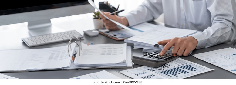 Corporate auditor calculating budget with calculator on his office desk. Dedicated accountant professional of accounting business company analyzing financial document to forecast income. Insight - Shutterstock ID 2366995343
