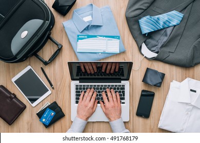 Corporate Businessman Packing His Bag And Planning A Business Trip, He Is Booking Flights Online Using A Laptop, Travel And Technology Concept