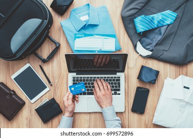 Corporate Businessman Packing His Bag And Planning A Business Trip, He Is Booking Flights Online Using A Laptop And A Credit Card, Travel And Technology Concept