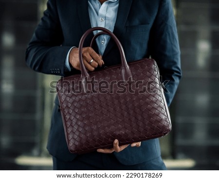 Corporate businessman in a suit with a maroon leather bag walking