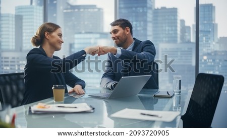 Corporate CEO and Investment Manager Talking, Using Laptop Computer while Sitting in Meeting Room in Office. Two Successful Businesspeople Fist Bump Over a Lucrative Real Estate Investment Deal.