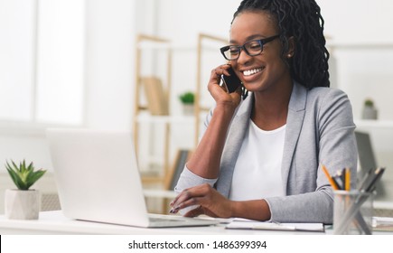 Corporate Communication. Black Businesswoman Talking On Mobile Phone Working On Laptop In Modern Office. Free Space - Powered by Shutterstock