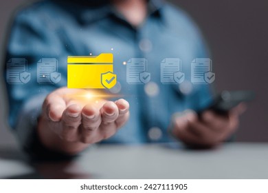 Corporate data management system concept. Personal data and corporate personal data protection. Person hold folder icon with shield protection on virtual screen for document secure confidential access - Powered by Shutterstock - Get 15% off with code: PIKWIZARD15