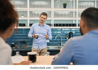 Corporate Employee Communicating With Coworkers In Office Kitchen