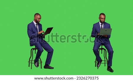 Corporate employee searching on online website, sitting on chair and using laptop in studio. Adult entrepreneur working with internet network page on wireless computer, full body greenscreen.