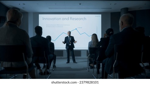 Corporate Event: Caucasian Male Tech CEO Giving Presentation To Colleagues or Investors In the Conference Room Of Innovative Startup Office. Man Talking About Business Objectives and Profit Margins.