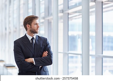 Corporate executive in a modern architectural setting looking confidently out of high rise windows - Powered by Shutterstock